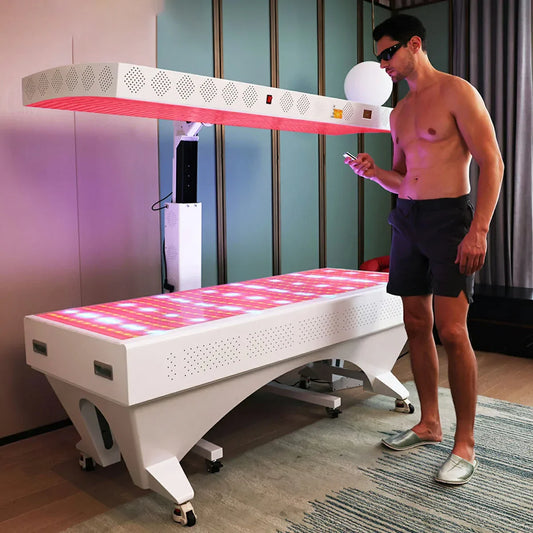 Man in sunglasses using control for full body red light therapy bed in modern room