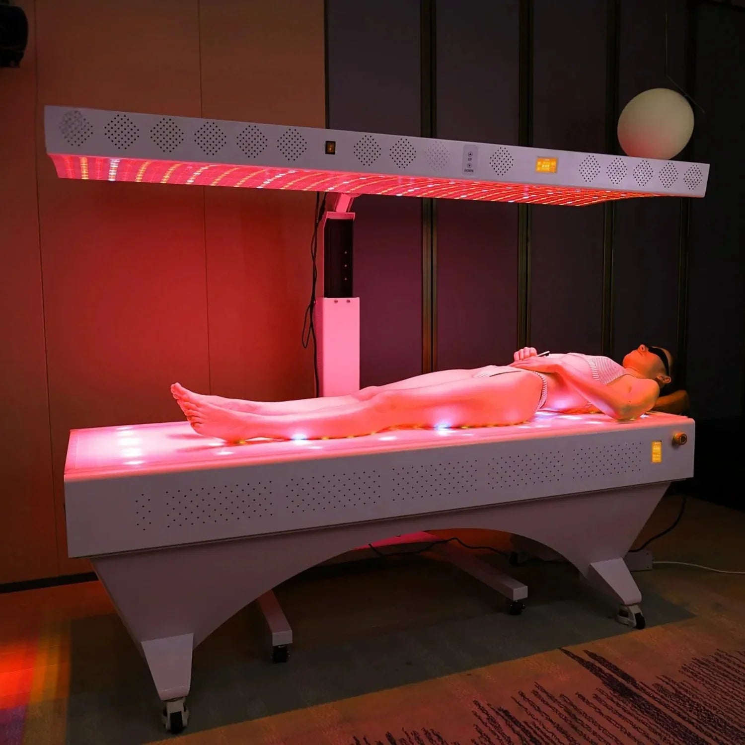 Person wearing sunglasses receiving red light therapy on full body in modern clinic